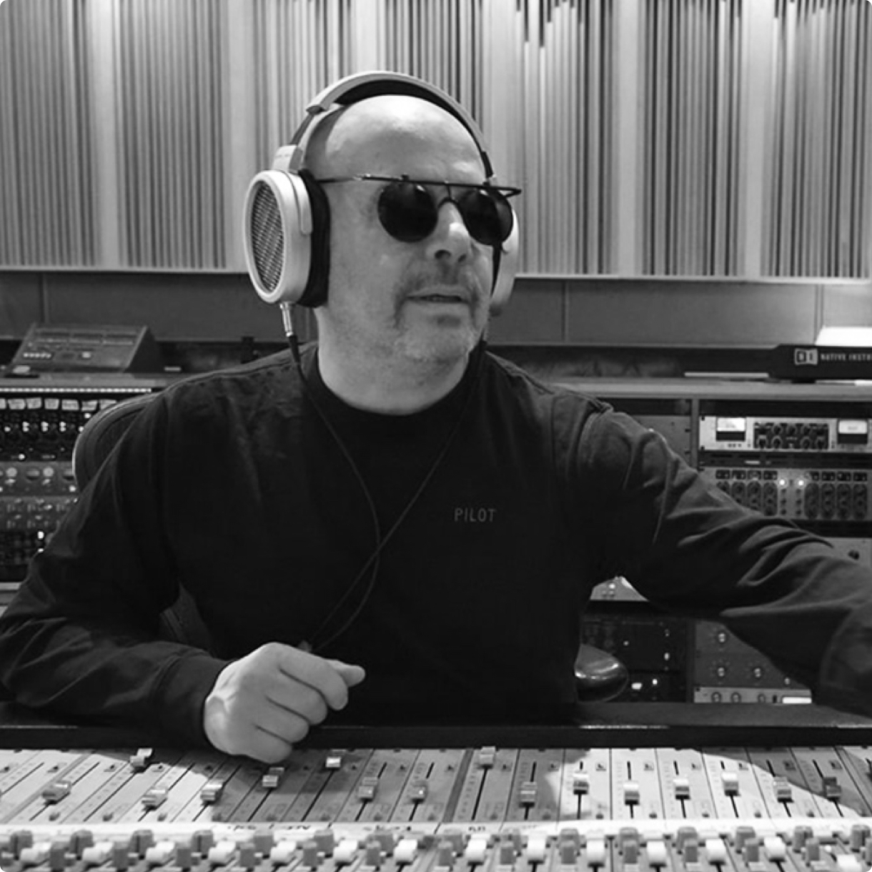 A man wearing sunglasses and a dark long sleeved t-shirt using the Sonoma Headphones to mix music